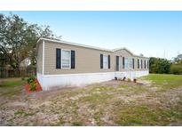 Tan single-wide manufactured home with black shutters and landscaping at 3046 Crystal Hills Dr, Lakeland, FL 33801