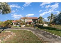 Sprawling two-story home with lush landscaping, circular driveway and a red metal roof at 6141 Palmetto Dr, Indian Lake Estates, FL 33855