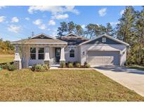 One-story home with gray siding, stone accents, and a two-car garage at 5830 Sw 121 St, Ocala, FL 34481