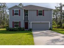Two-story house with gray siding, red shutters, and a two-car garage at 3681 Magnolia Dr, Indian Lake Estates, FL 33855