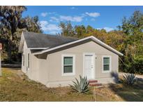Newly renovated house exterior, featuring a light beige stucco finish and a well-maintained lawn at 521 W Voorhis Ave, Deland, FL 32720