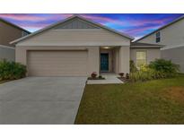 Tan house with a two-car garage and landscaped lawn at 1536 Axel Cir, Winter Haven, FL 33880