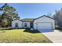 Newly constructed home with a two-car garage and landscaped lawn at 308 Bass Ct, Poinciana, FL 34759
