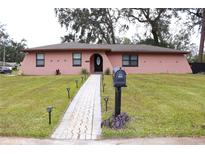 Pink house with a landscaped lawn, walkway, and mailbox at 2307 W Sugar Creek Dr, Lakeland, FL 33811