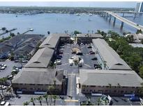 Aerial view of waterfront apartment building with parking and nearby bridge at 411 N Halifax Ave # 104, Daytona Beach, FL 32118