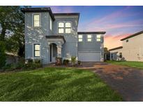 Two-story house with gray siding, a brick driveway, and landscaped lawn at 213 Aidans Ldg, Haines City, FL 33844