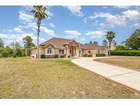 Single-story home with circular driveway, landscaping, and palm trees at 2715 Sw 177Th Place Rd, Ocala, FL 34473