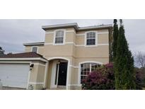 Two-story house with beige exterior, black door, and landscaping at 2938 Egrets Landing Dr, Lake Mary, FL 32746