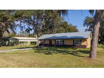 House exterior features a metal roof, carport, and landscaped lawn at 1507 Hontoon Rd, Deland, FL 32720