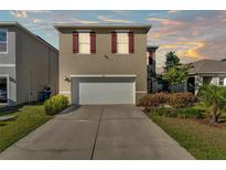 Charming two-story home featuring a two-car garage, landscaped yard, and classic red shutters at 163 Tiny Flower Rd, Davenport, FL 33837