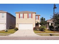 Two-story house with attached garage and landscaping at 163 Tiny Flower Rd, Davenport, FL 33837