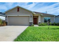 Charming single-Gathering home with a well-manicured lawn, beige exterior and a two-car garage at 2871 Parkfield Rd, St Cloud, FL 34772