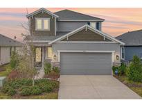 Two-story house with gray siding, two-car garage, and landscaping at 2557 Village Lakes Blvd, Lakeland, FL 33805