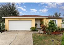 Attractive yellow house with a white garage door and well-maintained landscaping at 1504 Fort Meade Pl, Poinciana, FL 34759