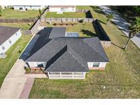 An aerial view showcases the home's dark shingled roof and fully fenced yard, with a covered patio inviting outdoor relaxation at 20 Hemlock Trl, Ocala, FL 34472