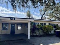 Tan ranch house with carport, dark door, and mature landscaping at 565 Forrest Dr, Bartow, FL 33830