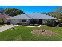 Charming single-story home featuring a manicured lawn, mature landscaping, and a welcoming facade at 27100 Racquet Cir, Leesburg, FL 34748