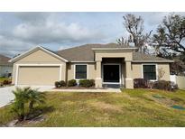 Tan house with a two-car garage, landscaped lawn, and a covered entryway at 2793 Hudson St, Lakeland, FL 33810