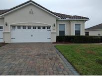 Tan two-car garage villa with paved driveway and landscaped lawn at 2491 Harwich Dr, Kissimmee, FL 34741