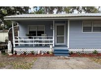 Inviting covered front porch featuring a seating area and decorative plants at this quaint home at 1268 Cr 436, Lake Panasoffkee, FL 33538