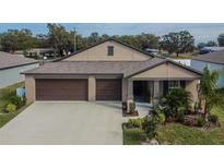 Tan two-car garage home with brown garage doors, landscaping, and a walkway at 2954 Flying Blackbird Rd, Bartow, FL 33830