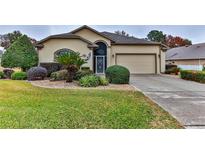 Tan one-story house with landscaped yard, attached garage, and driveway at 706 Lake Diamond Ave, Ocala, FL 34472
