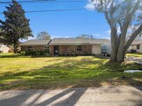Charming single-story brick home featuring a well-maintained lawn and mature shade trees at 5040 Kirkland Rd, Lakeland, FL 33811