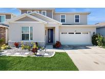 Two-story house with a two-car garage, landscaping, and stone accents at 1076 Sugarwood St, Davenport, FL 33837