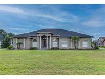 Large one-story home with a stucco exterior, landscaped lawn, and a three-car garage at 164 Sunrise Hill Ln, Auburndale, FL 33823