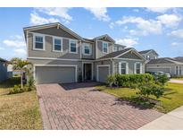 Charming two-story home featuring a brick driveway, well-manicured lawn, and inviting curb appeal at 3200 Canna Lily Pl, Clermont, FL 34711