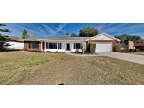Brick ranch house with a white front door, attached garage, and well-manicured lawn at 6821 Rembrandt Dr, Orlando, FL 32818