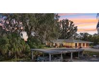 Lakeside home featuring a boat dock, single-story structure, and mature trees draped in Spanish moss at 8309 W Lake Marion Rd, Haines City, FL 33844