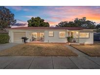 Charming single-story home featuring a red metal roof and well-maintained front lawn under a colorful evening sky at 11213 Se 53Rd Ct, Belleview, FL 34420