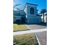 Two-story home with gray exterior, three-car garage, and landscaped lawn at 1851 Goblet Cove St, Kissimmee, FL 34746