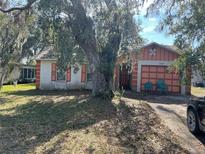 Ranch-style house with orange accents, mature landscaping, and a spacious yard at 309 E Pine St, Davenport, FL 33837