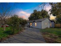 Charming single-story home with a well-maintained lawn, a paved driveway, and mature trees against a beautiful sky at 116 Woodlane Ave, Wildwood, FL 34785