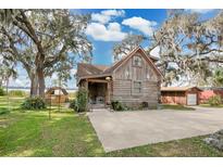 Charming log cabin home with a spacious driveway and lush green lawn at 114 Tempsford Rd, Auburndale, FL 33823