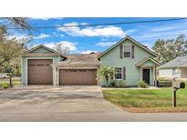 Charming green home with a well-manicured lawn, multiple garages, and stone accents at 506 Parrott Rd, Auburndale, FL 33823