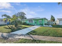 Charming single-story green home with a well-manicured lawn and a concrete driveway leading to the entrance at 38 Seaside Dr, Ormond Beach, FL 32176