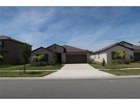 Inviting single-story home featuring a well-manicured lawn and a spacious two-car garage on a sunny day at 2206 Old Mining Rd, Lakeland, FL 33801