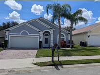 Charming single-story home featuring a two-car garage and mature landscaping, including palm trees at 131 Vine Dr, Davenport, FL 33837