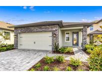Charming home featuring stone accents, a two-car garage, and manicured landscaping at 7709 Somersworth Dr, Kissimmee, FL 34747