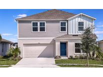 Charming two-story home with gray siding, a blue front door, well-manicured lawn, and an attached two-car garage at 1600 Ellesmere Ave, Haines City, FL 33844