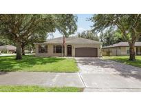 Charming single-story home featuring a well-manicured front lawn, two-car garage and inviting front door at 416 Country View Cir, Deland, FL 32720