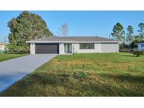 Charming single-story home with a well-maintained lawn and modern garage at 2310 Laguna Dr, Indian Lake Estates, FL 33855