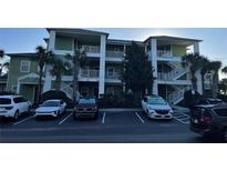 Three-story building with green facade, white railings, palm trees, and a parking lot in front at 705 Gran Bahama Blvd # 705, Davenport, FL 33897