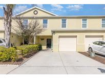 Two-story townhome with one-car garage, well-kept lawn, and yellow siding at 380 Arbor Lakes Dr, Davenport, FL 33896