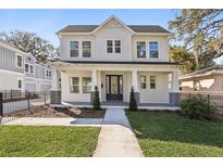 Inviting two-story white home boasts a manicured lawn, walkway, covered porch, and a welcoming entrance at 2308 Depauw Ave, Orlando, FL 32804