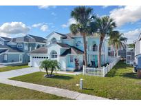 Charming two-story home features tropical landscaping, an attached garage, and a delightful turquoise-colored front door at 2410 Berkshire Ct, Kissimmee, FL 34746