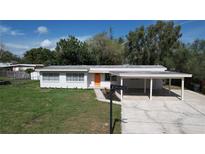 Charming single-story home with a carport, tidy landscaping, and a bright orange front door at 1625 Avenue D Ne, Winter Haven, FL 33881